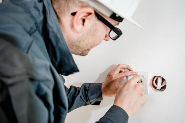 Elektriker i Karlskoga som håller på att installera ett eluttag på en vägg.